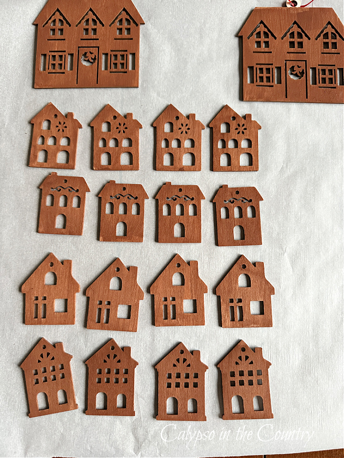 Brown painted wooden house ornaments drying on parchment paper
