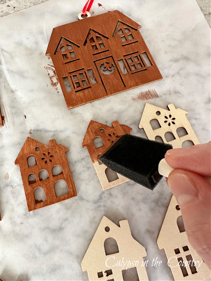 Hand painting wooden gingerbread house ornaments with brown paint