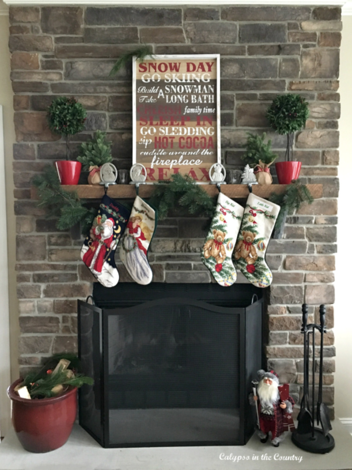 Stone fireplace Christmas mantel with leaning snow word art and hanging stockings