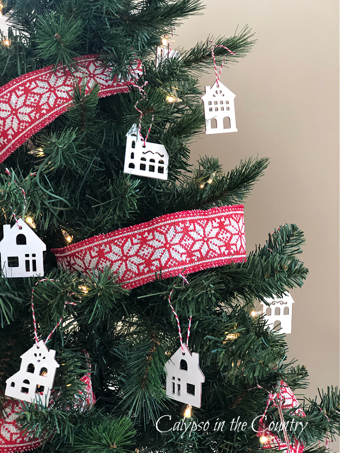 Red ribbon and white house ornaments on Christmas tree