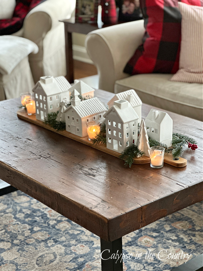 White ceramic houses and candles on coffee table - Christmas coffee table decorating ideas