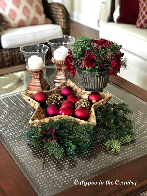 Ornaments in star shaped basket with greenery and candles on Christmas coffee table