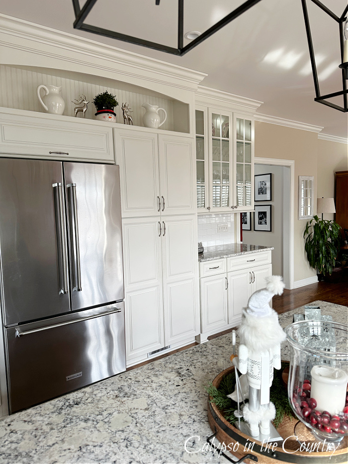 Wall of white cabinets and stainless refrigerator