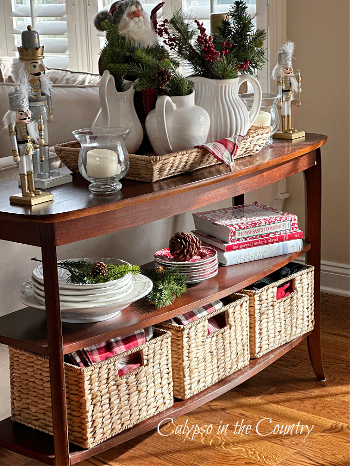 Console table decorated with baskets and white pitchers for Christmas 