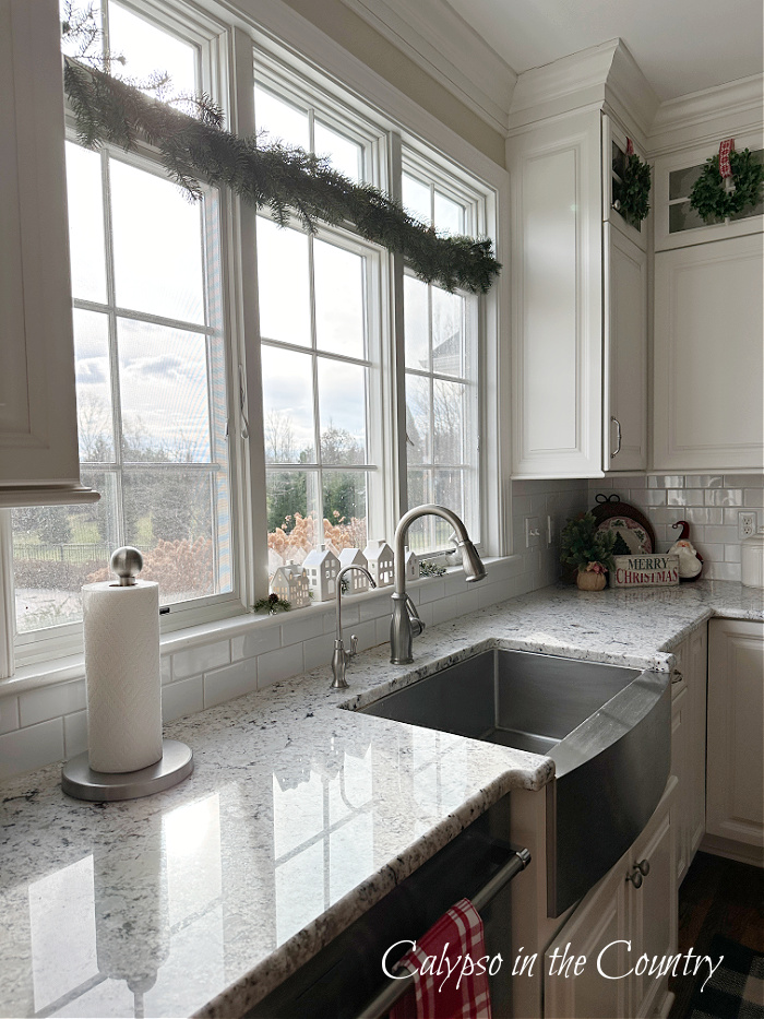 Christmas garland hung on transom window over kitchen sink 