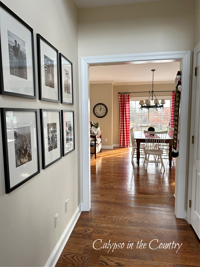 Hallway with black and white photos at entrance to kitchen with red checked curtains - cozy Christmas home tour