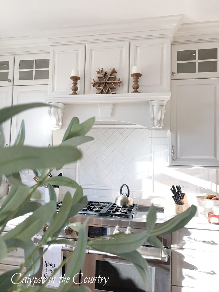 White kitchen with wooden winter accessories on stove mantel