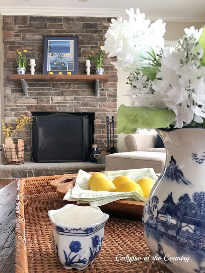 Stone fireplace with blue and yellow accessories and rattan tray on coffee table
