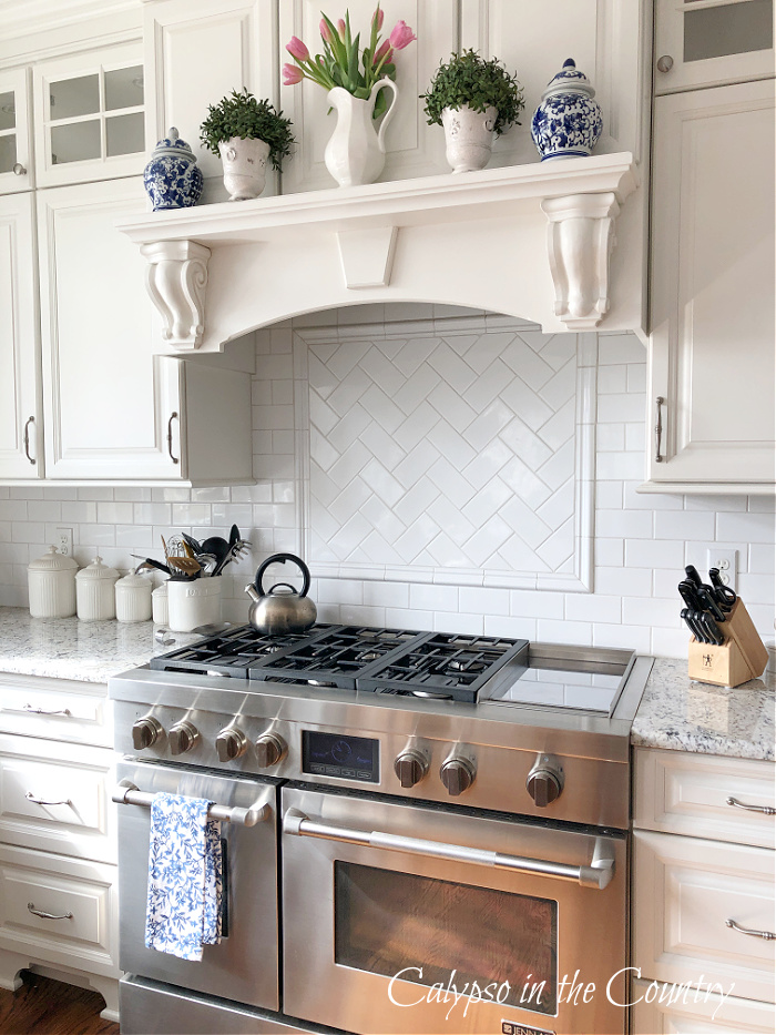 Stainless steel stove with white cabinets and spring decor on stove mantel shelf 