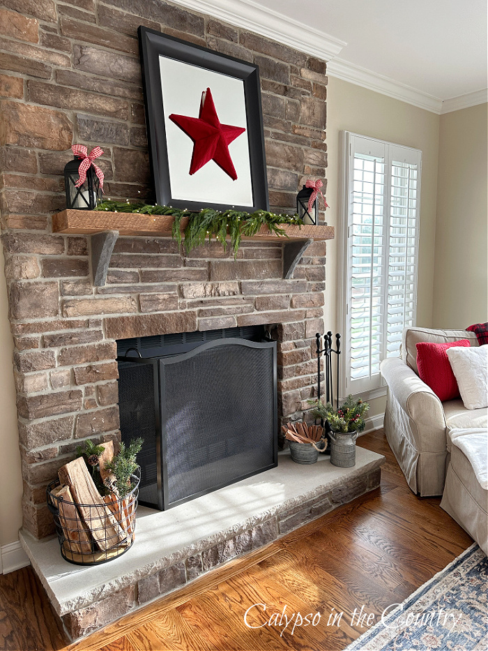 stone fireplace decorated with black mirror, red star and garland 
