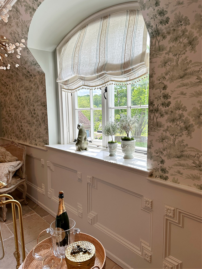 Arched window, wallpaper and decorative moulding in primary bathroom 