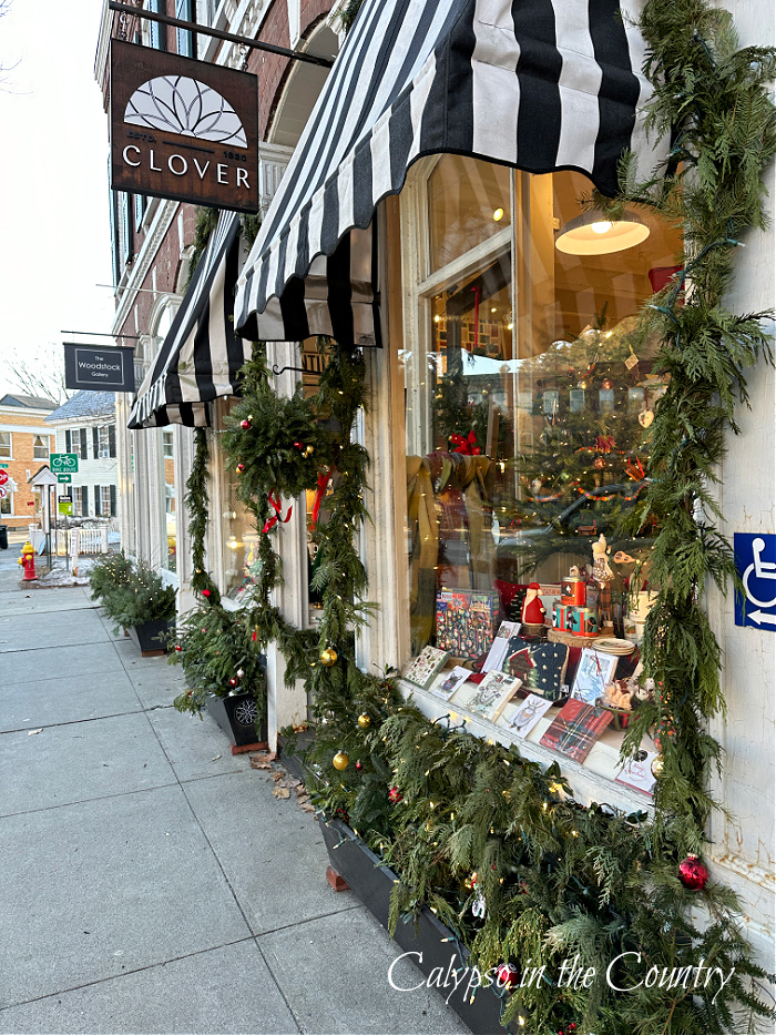 Storefront with black and white striped awnings and Christmas garland - goodbye December hello January