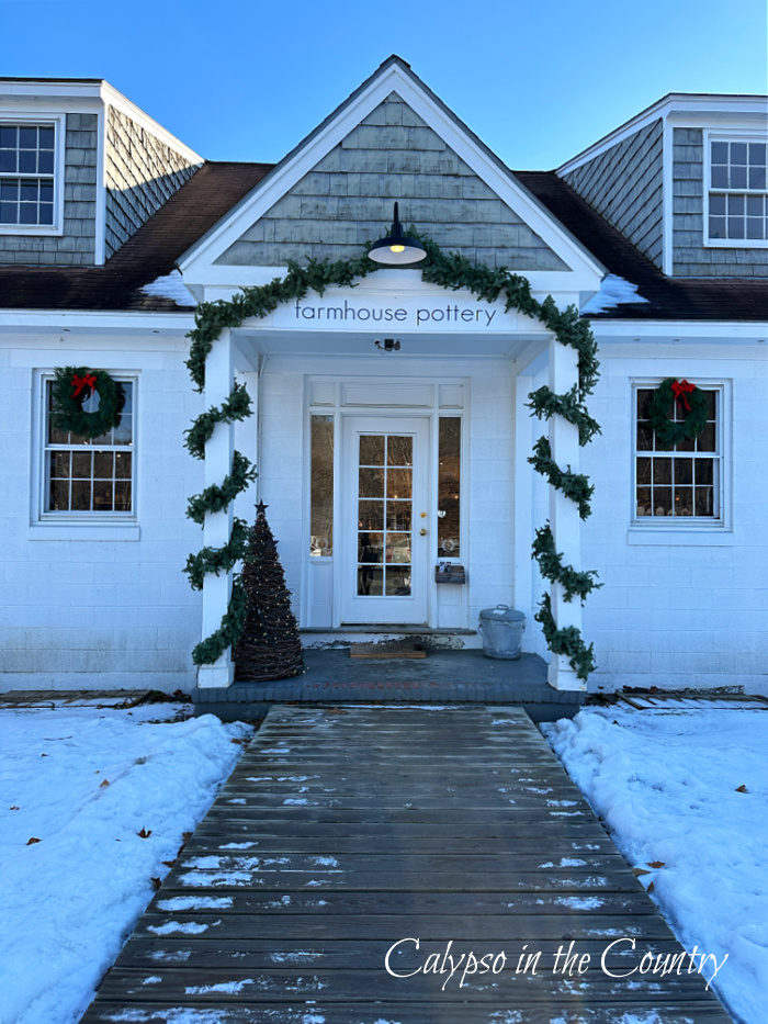 White Farmhouse Pottery store front decorated for Christmas with garland - goodbye December hello January 