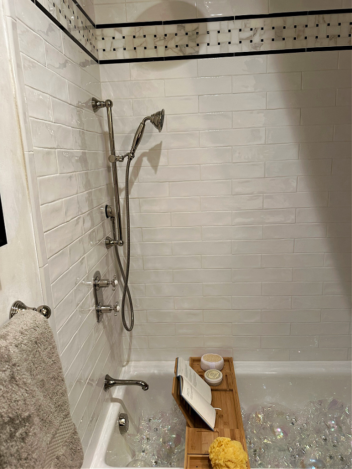 Shower and bathtub with white subway tile and basketweave border