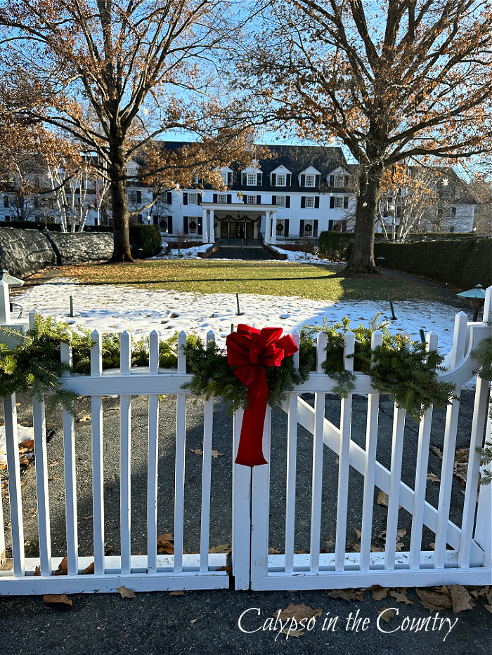 White gates with red bow and large white hotel in the background - Woodstock Inn at Christmas - goodbye December hello January