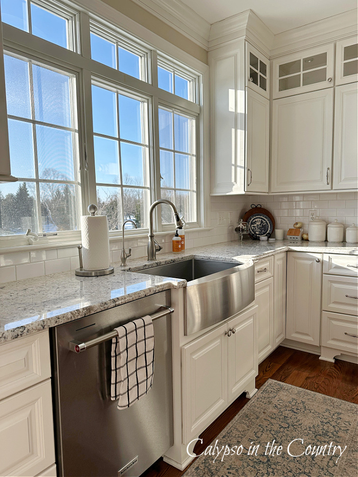 Blue sky in windows over sink in white kitchen - January decorating ideas