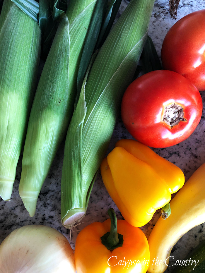 Ears of corn, red tomatoes and yellow bell peppers - goodbye july hello august