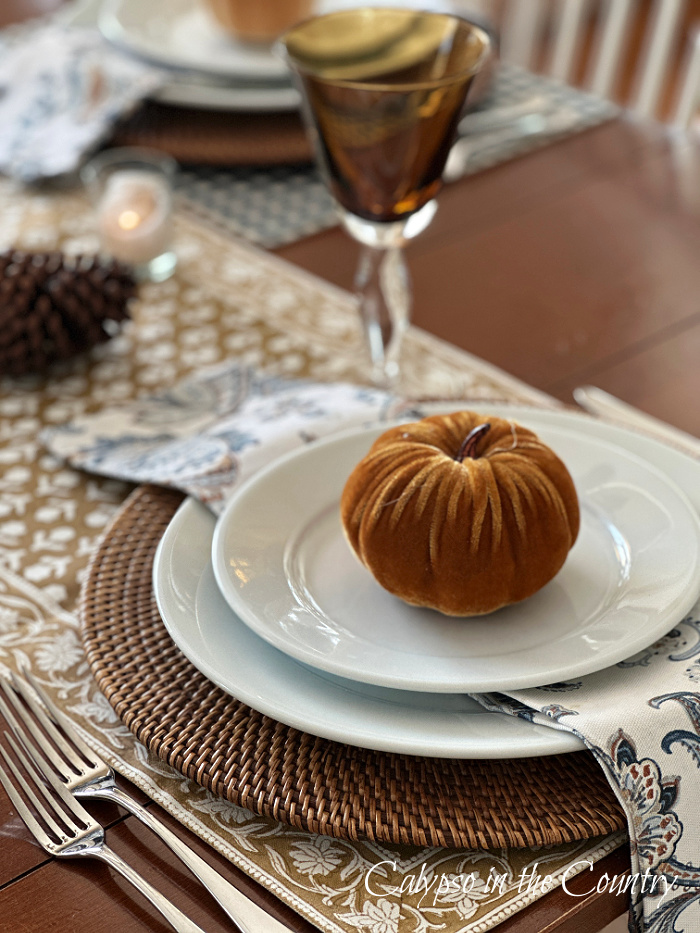 Table place setting with white plates, brown velvet pumpkin and block print table runner - fall vibes