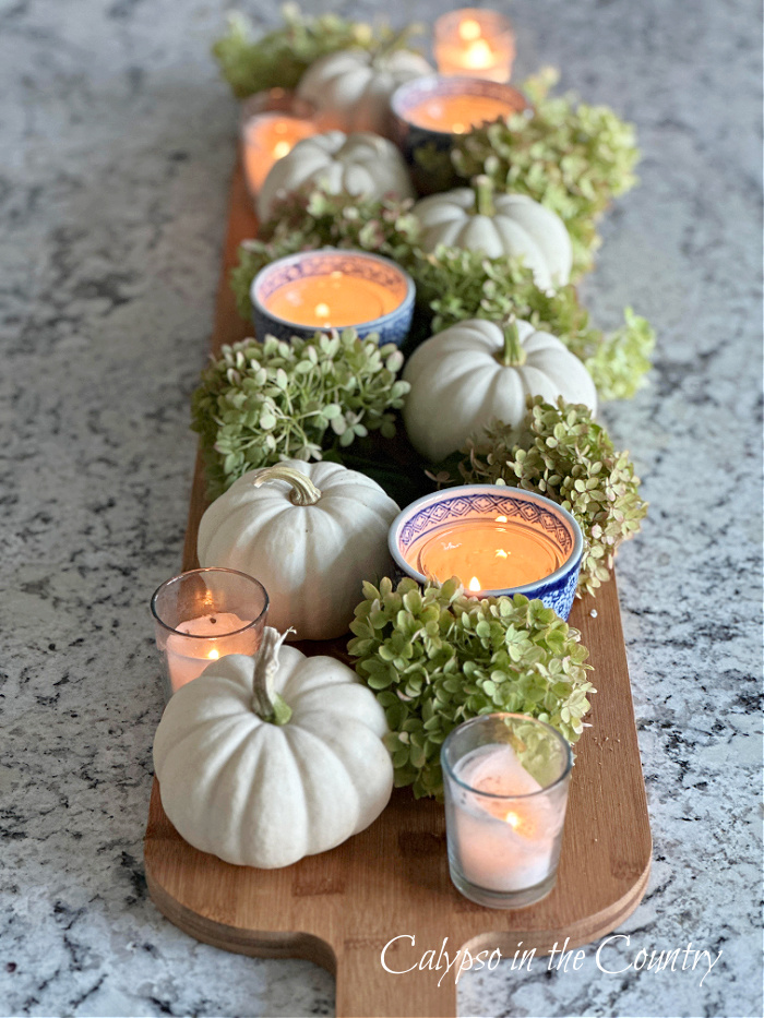 white pumpkins, candles, hydrangeas and blue and white porcelain on long bread board for fall