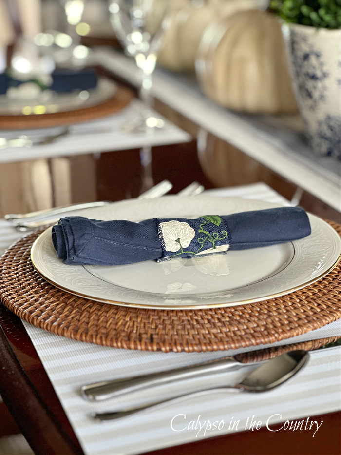 Dining place setting with white plate and navy blue rolled napkin - blue and white fall decorating ideas
