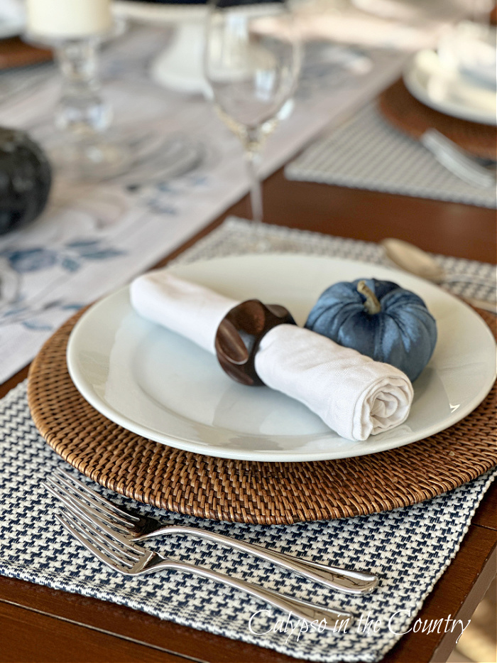 table place setting with white plate, blue and white placemat, white napkin and blue velvet pumpkin - fall decorating ideas 