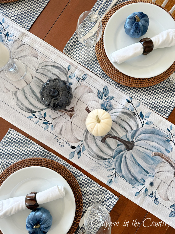 Top view of fall table decorated with blue velvet pumpkins and blue and white pumpkin table runner