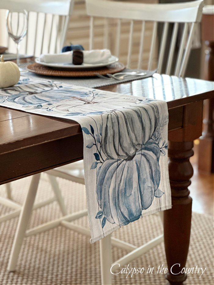 blue pumpkin table runner on brown wood table - blue and white fall decorating ideas