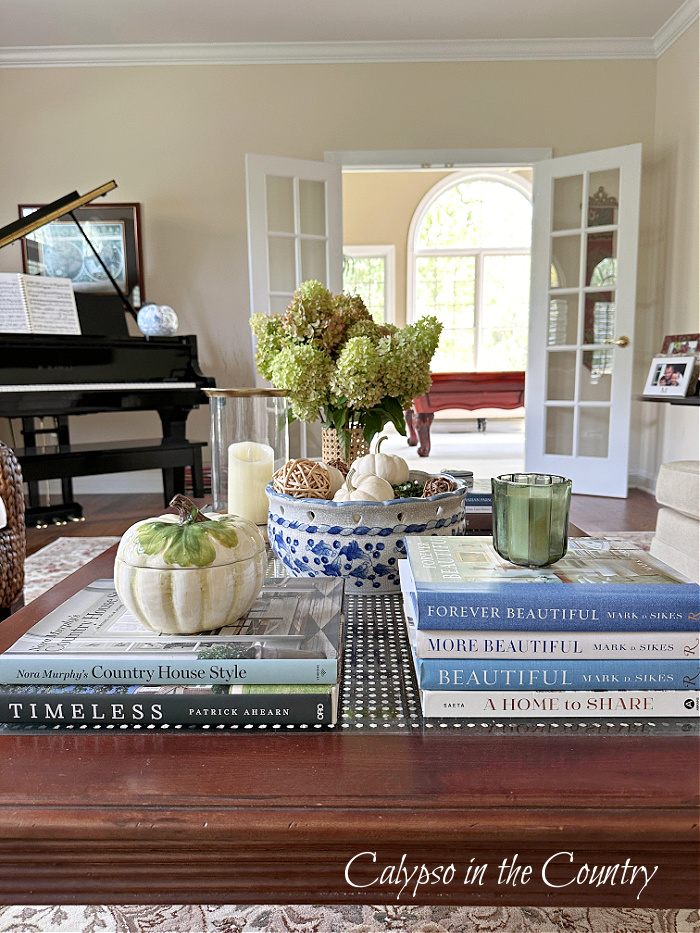 coffee table styled with stacks of books, hydrangeas and blue and white fall decorating ideas