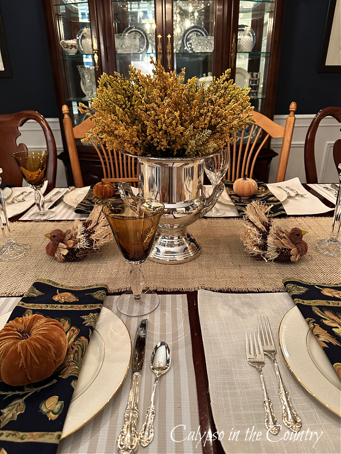 Silver champagne bucket centerpiece with golden stems on middle of Thanksgiving table - hello holiday season