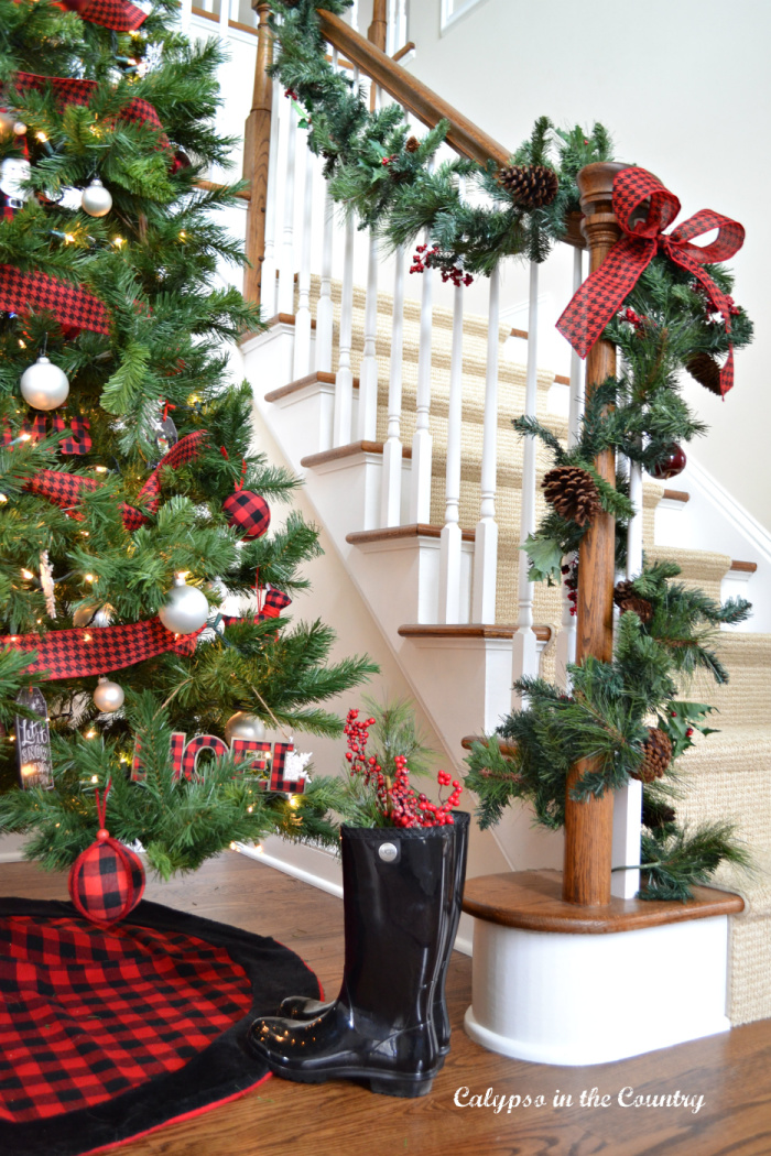 Staircase with garland and foyer Christmas tree decorated with red and black - hello holiday season