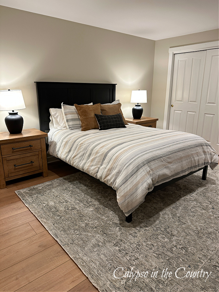 Black bed with light wood nightstands and gray area rug - neutral bedroom makeover