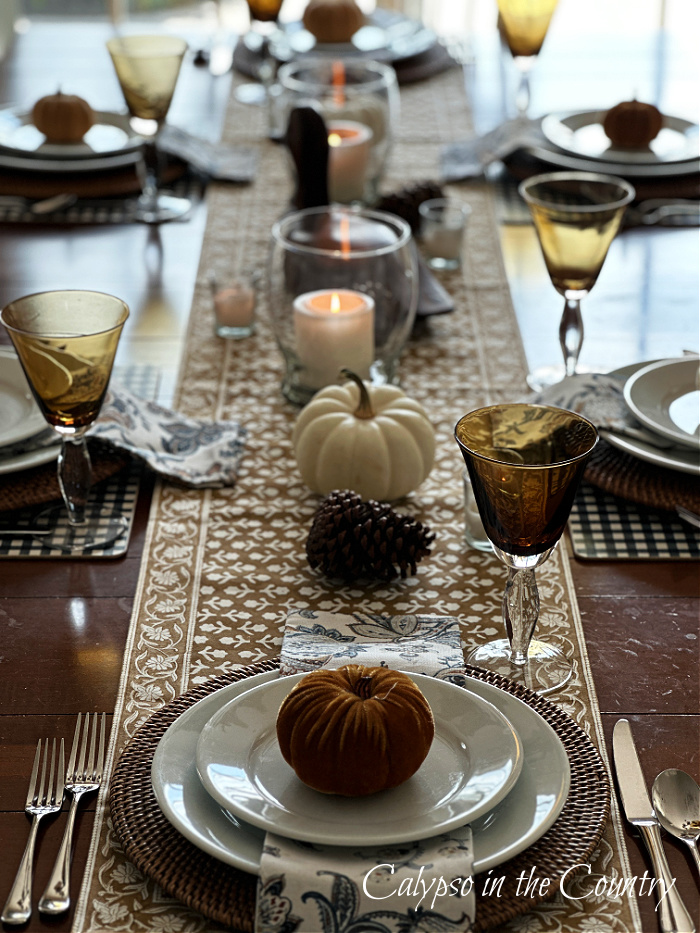 Long view of neutral fall tablescape with white plates and pumpkins