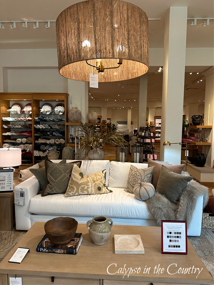 Round woven pendant over white sofa styled with fall pillows