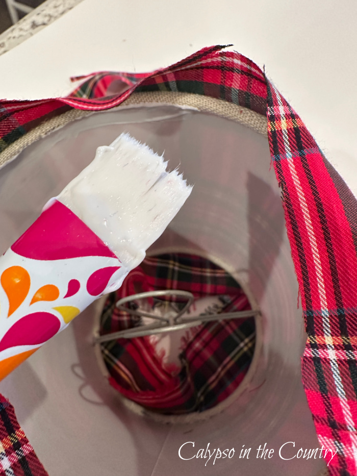 Craft brush with adhesive attaching plaid fabric to lampshade