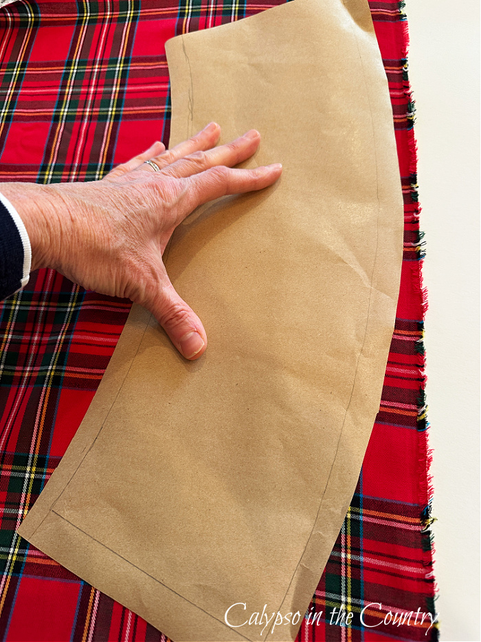 Red plaid fabric and hand holding kraft paper template - DIY Plaid Lampshades