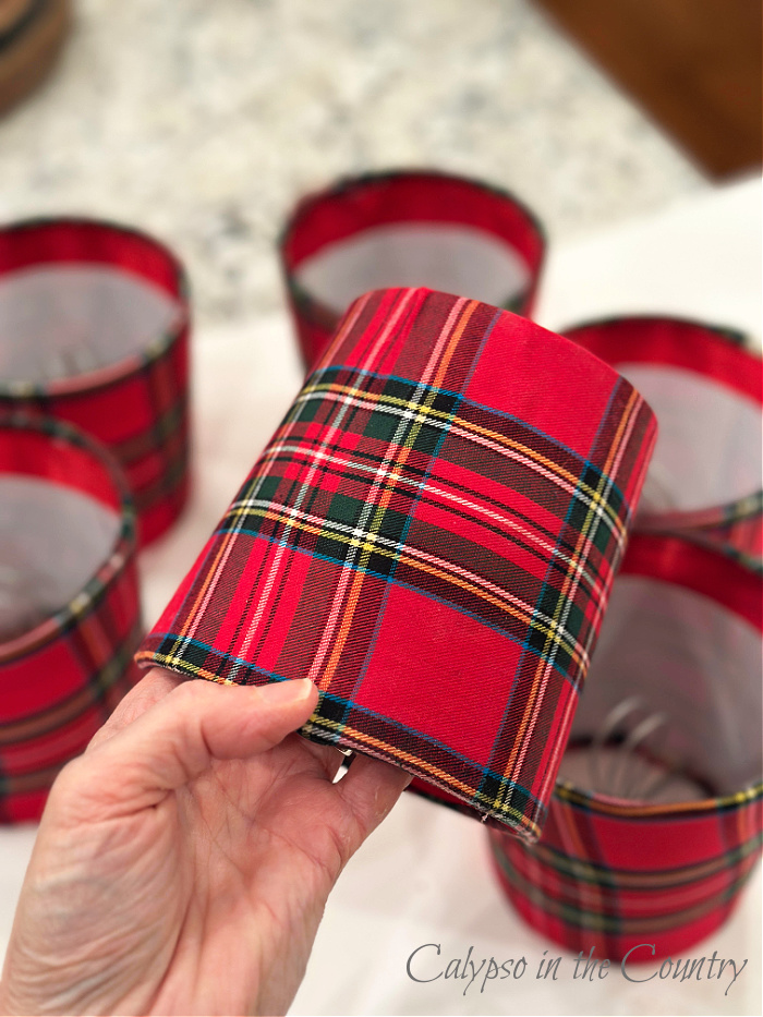 Hand holding a red diy plaid lampshade with rest of lampshades in background