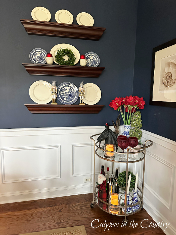 Navy blue walls with dark wood floating shelves and round gold bar cart - Ralph Lauren Christmas dining Room