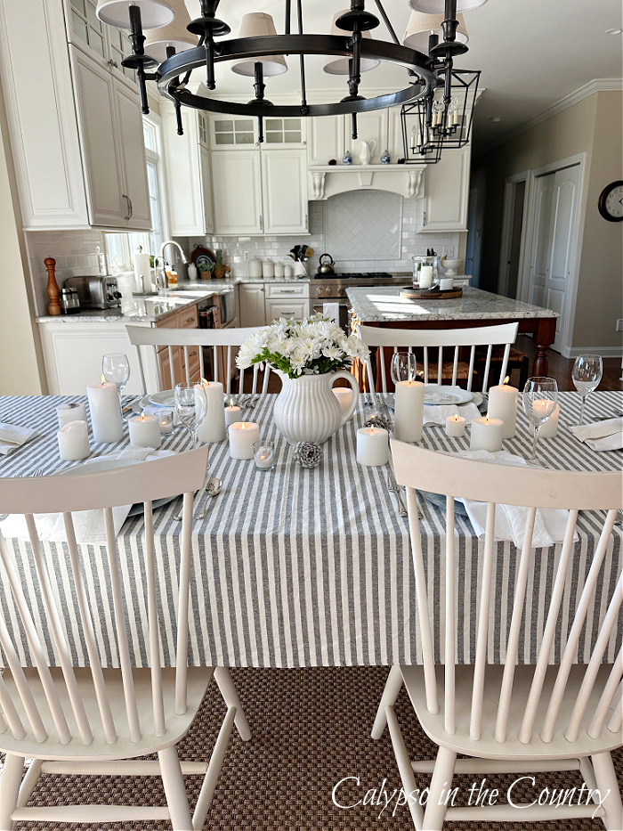winter white table setting with gray and white striped table cloth and white chairs
