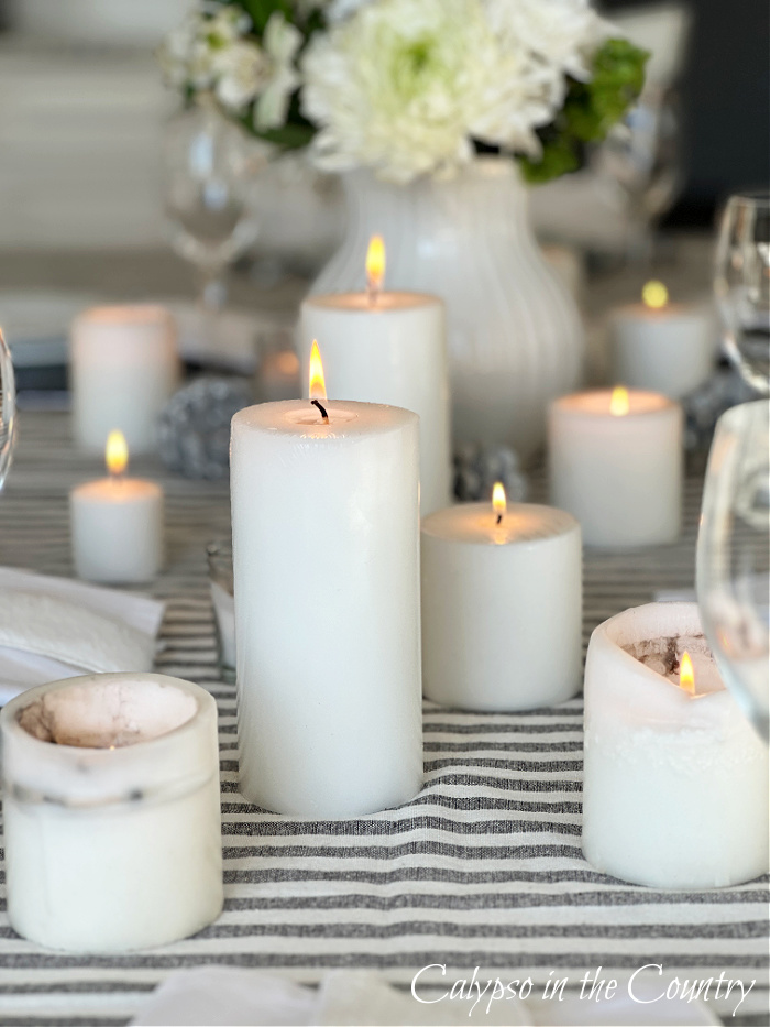 group of lit white candles on table with striped tablecloth