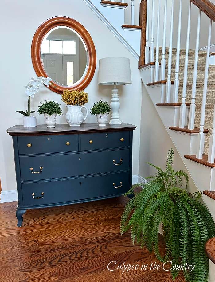 blue dresser next to staircase with fern plant on wood floor - fern decorating ideas 