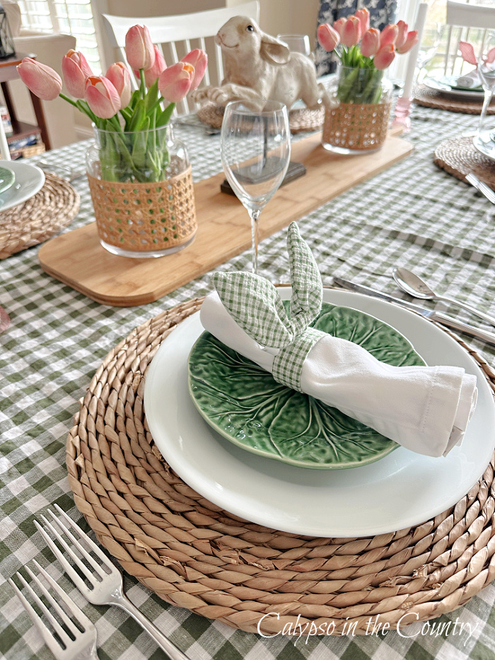Green gingham tablecloth with pink tulips and green and white layered place settings - Easter brunch table setting