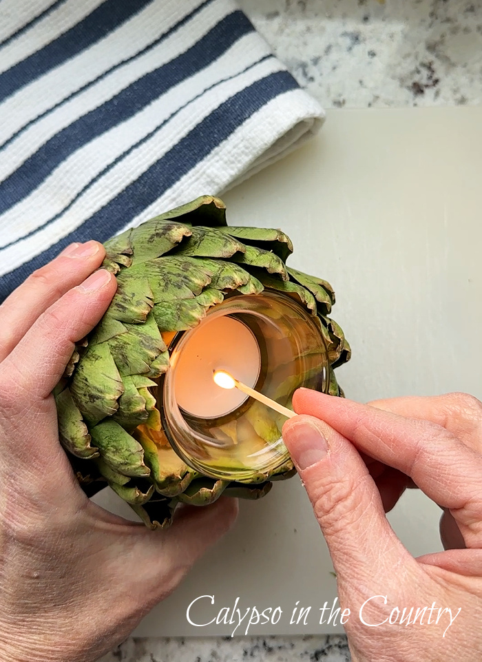 Hand lighting tealight candle in a DIY artichoke candle holder