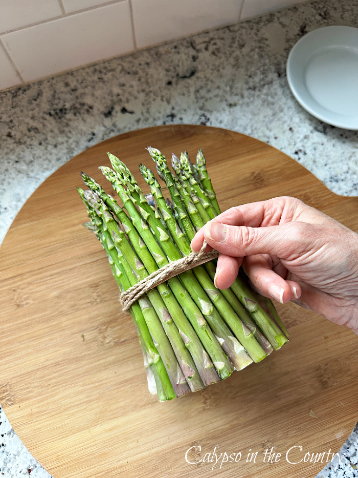 Hand tying twine around asparagus vase