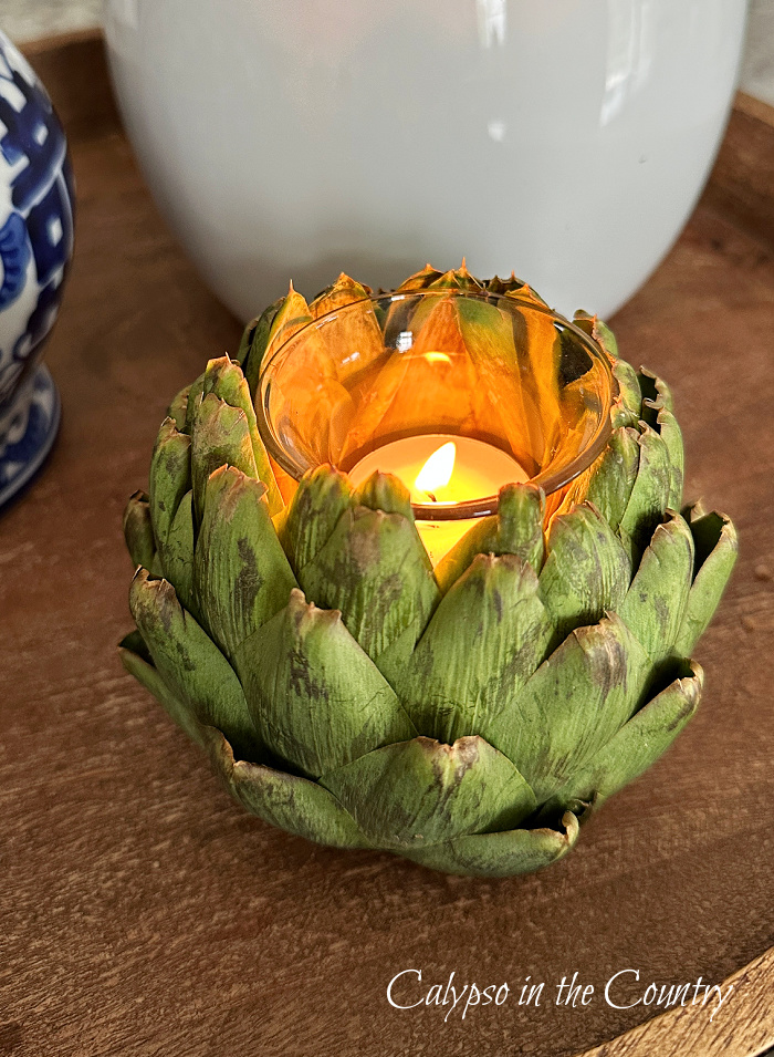 Artichoke candle holder with lit tealight candle inside.