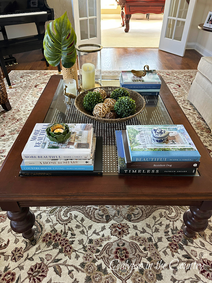 Dark wood coffee table styled for spring with stacks of books, candles, and greenery - March wrap up