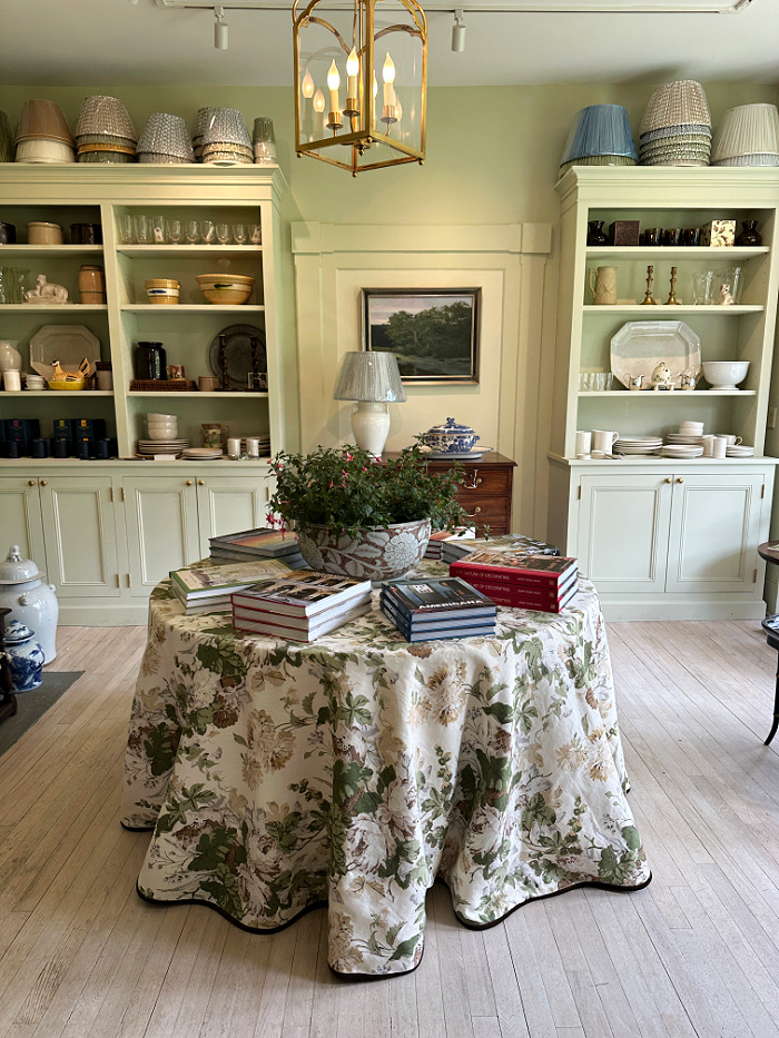 Store display with shelves, and round table with floral table skirt - Welcome May