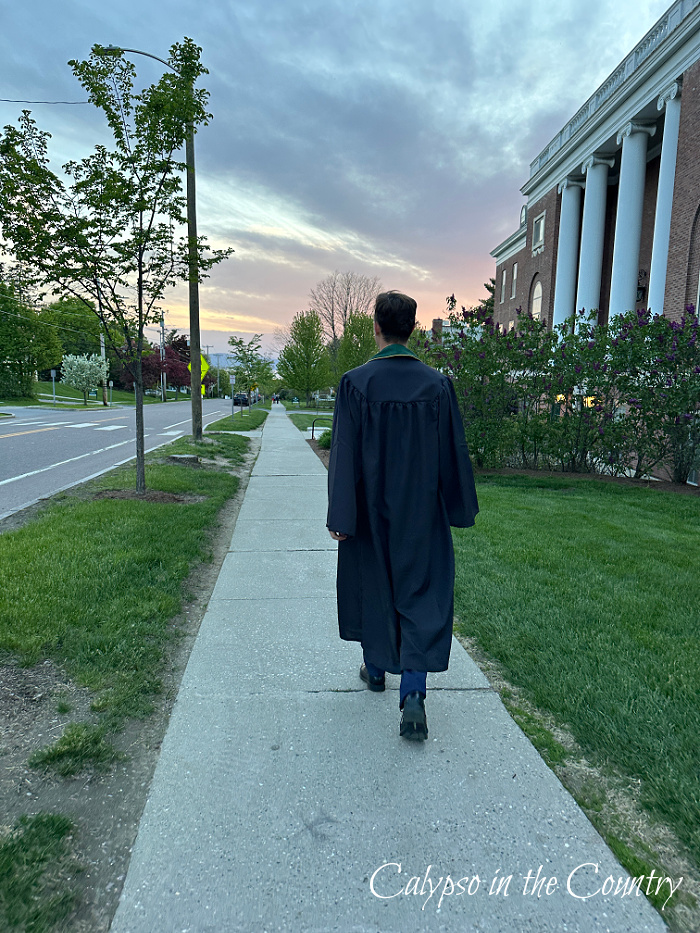 Man wearing graduation gown and walking towards sunset - May Wrap Up