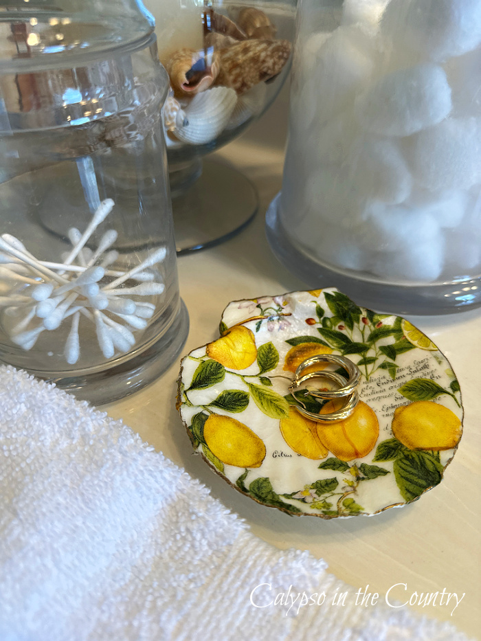 Lemon print trinket tray with earrings on bathroom counter - how to decoupage shells with napkins
