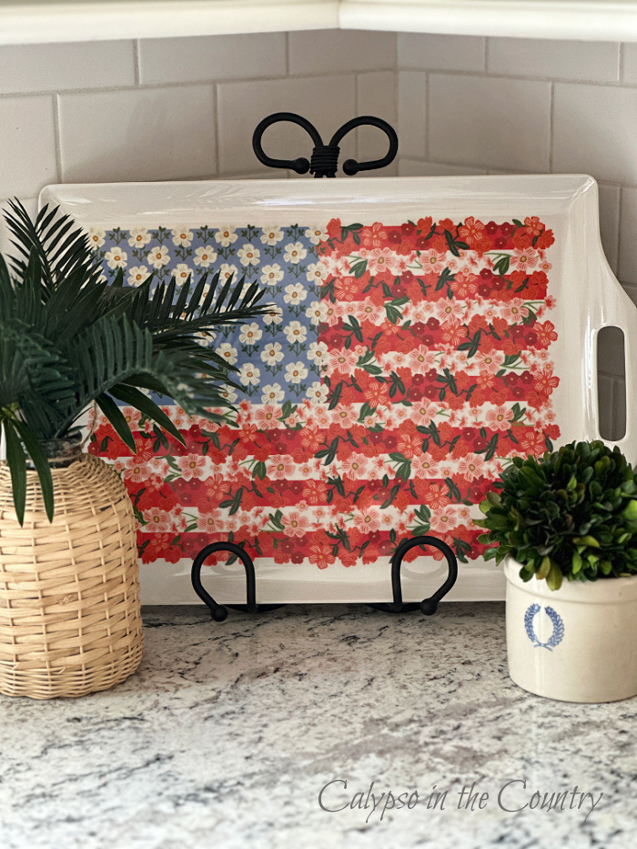Flag tray on stand with faux plants on kitchen counter