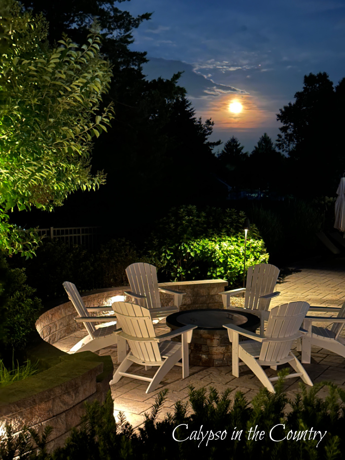 Full moon behind trees with Adirondack chairs and firepit at bottom of photo - June wrap up